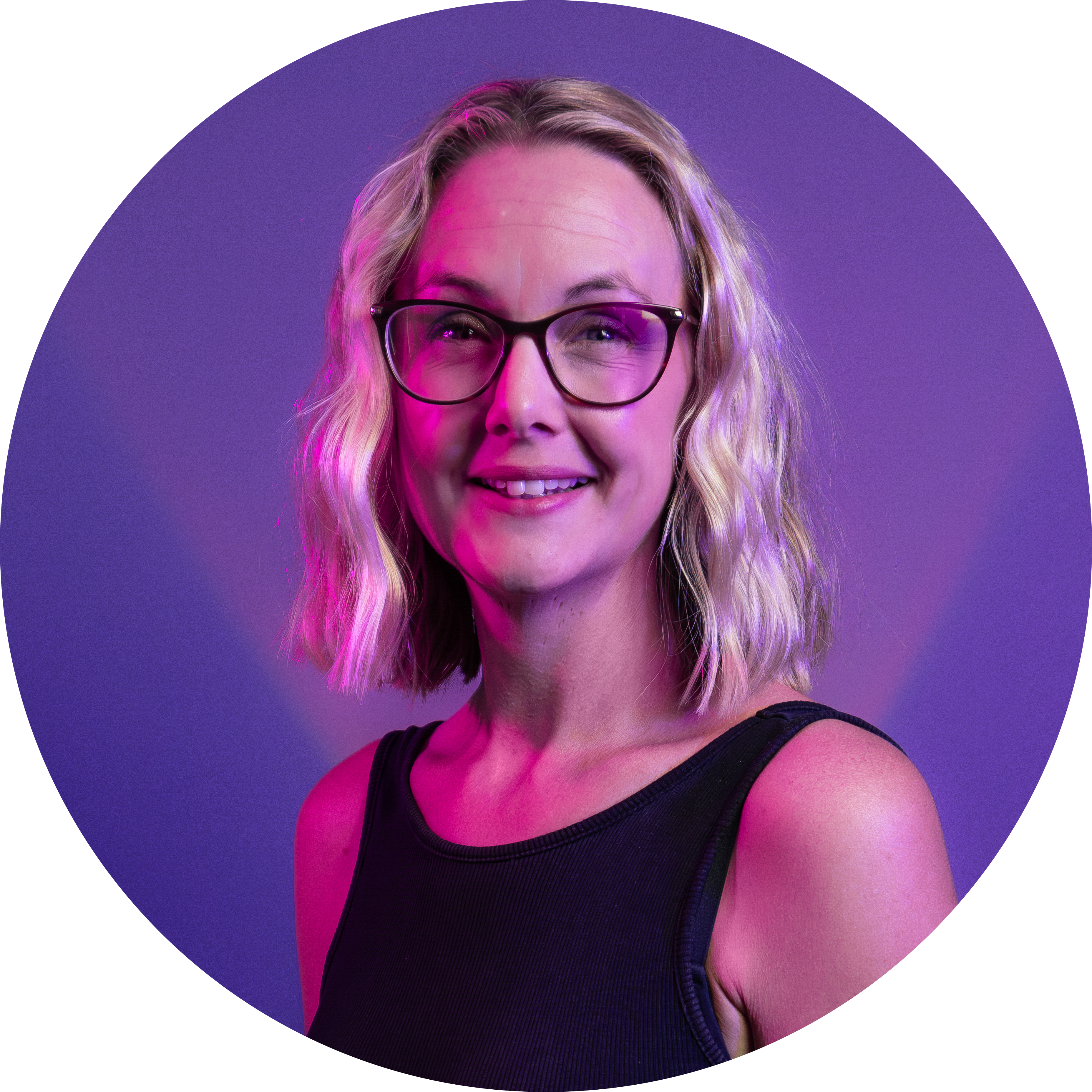 Sam Slee – a blonde woman with shoulder length hair and dark rimmed glasses – smiles against a purple background.