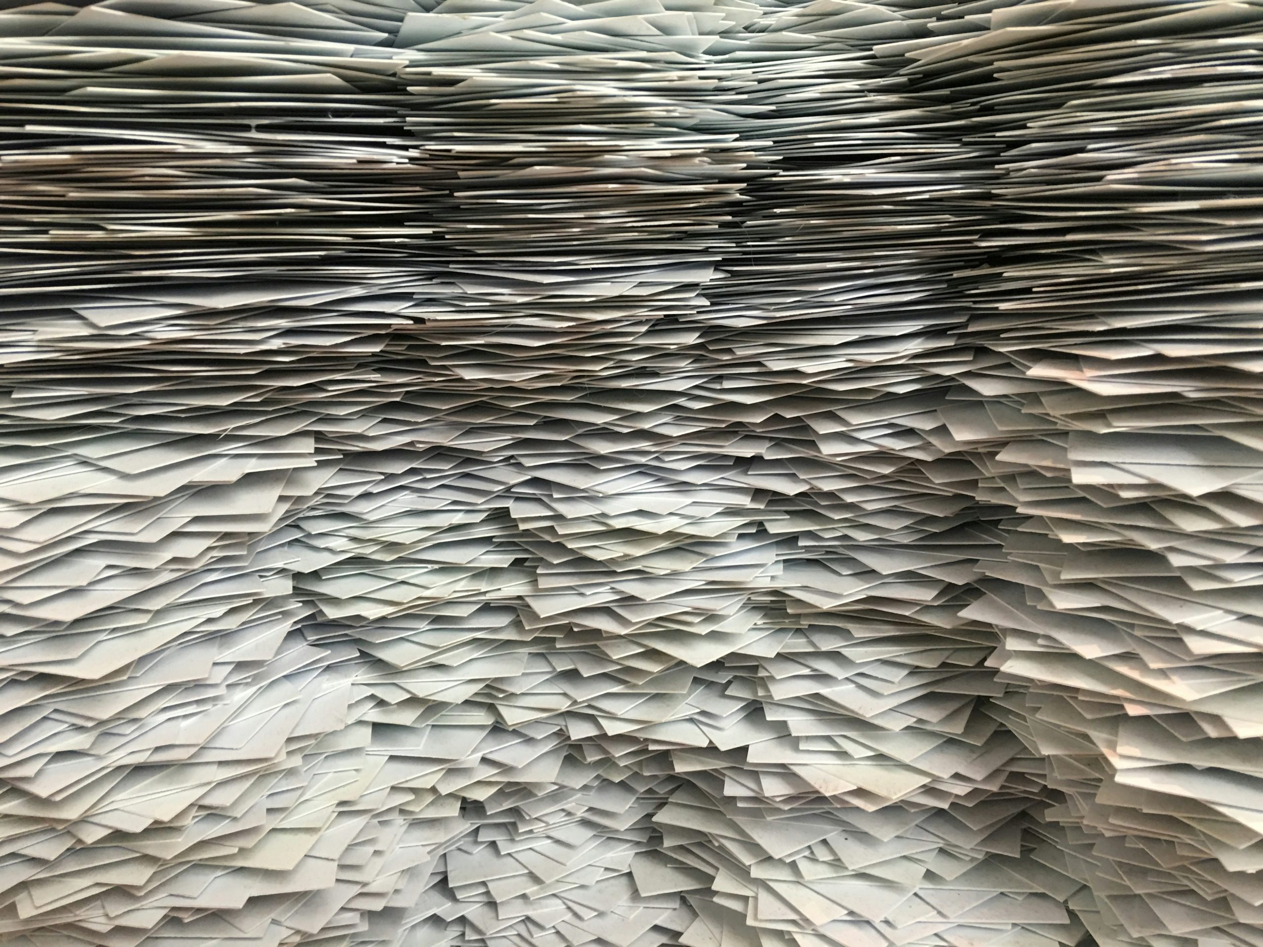 tonnes of envelopes balanced in stacks that interlace from the head of the image to the foot